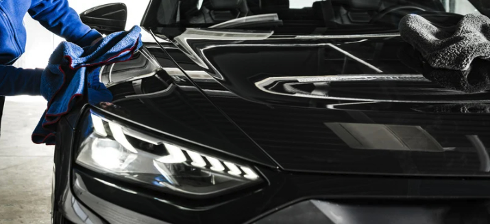 Technician completing exterior detailing on a black car in Ocean County NJ, polishing the hood for a deep shine during a mobile car detailing service.